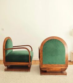 two green chairs sitting next to each other in a room with wood floors and white walls