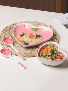 two heart shaped bowls and spoons on a table with a book in the background