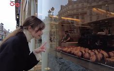 a woman pointing at pastries in a bakery window