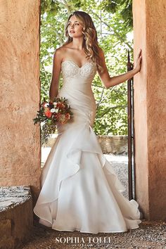 a woman in a wedding dress is posing for the camera