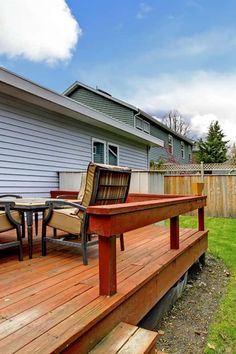 a wooden deck with chairs on it next to a house