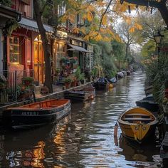 several boats are parked on the side of a canal in front of buildings and trees