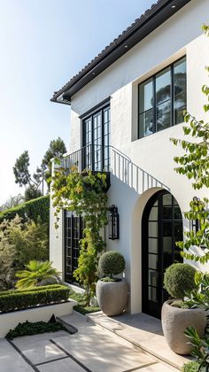 a white house with two large planters in front of it and an entry way leading to the second floor