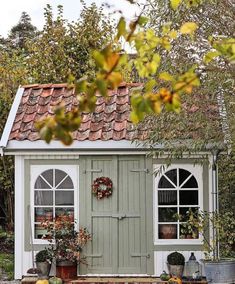 a small shed with windows and potted plants