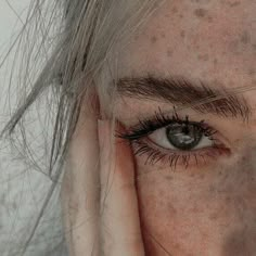 a woman with freckled hair holding her hand up to her face