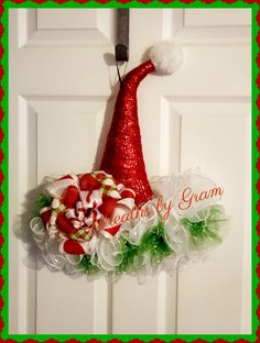 a red and green christmas wreath hanging on a door with candy canes in it