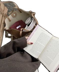 an open book sitting on top of a chair next to a handbag and purse