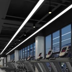 there are many treadmills lined up in the gym with windows overlooking the city