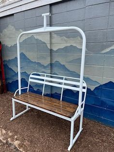 a white metal bench sitting next to a wall