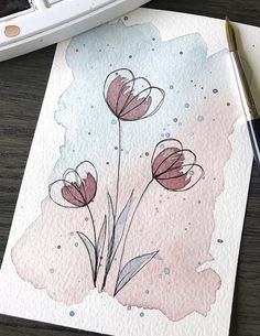 a watercolor painting of pink flowers on paper next to a brush and ink pen