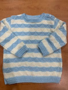 a blue and white striped sweater sitting on top of a wooden table next to a pair of scissors