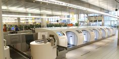 an airport baggage claim area with machines and people