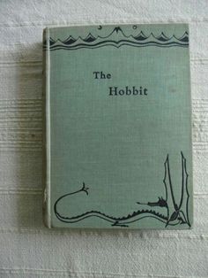 the hobbit is written in black ink on a green book with white linens