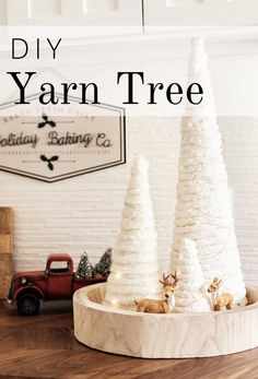 the diy yarn tree is sitting on top of a wooden tray with deer figurines