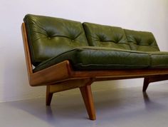 a green leather couch sitting on top of a wooden frame