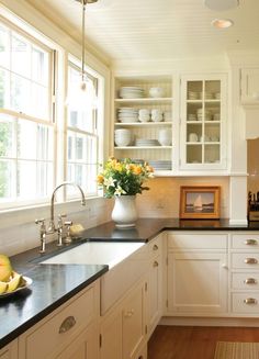 a kitchen with white cabinets and black counter tops