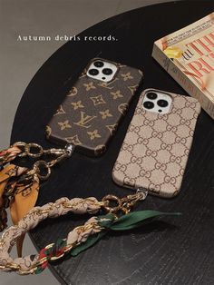 three cell phones sitting on top of a table next to a book and chain necklace