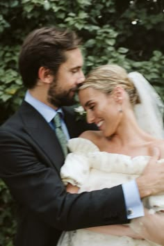 a bride and groom embracing each other in front of some greenery at their wedding