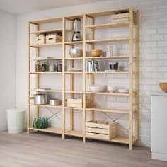 a wooden shelf filled with pots and pans next to a white brick wall in an empty room