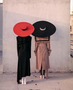 two women with hats on their heads standing next to each other in front of a wall