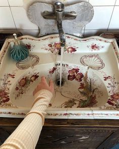 a person is washing their hands in a sink with floral designs on the bottom and sides