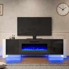 an entertainment center with a large television and blue flames on the side, in front of a wall clock