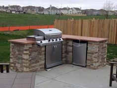 an outdoor kitchen with grill and seating area