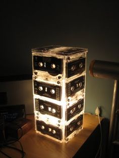 a stack of cassettes sitting on top of a wooden table next to a lamp