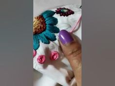 a woman's hand with purple nail polish and flower design on her white shirt