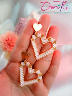 a person holding two small heart shaped earrings in their hand with the word doritte written on it