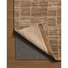 an area rug that has been placed on top of a wooden floor with a brown and beige color scheme