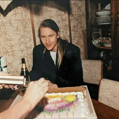 a man sitting at a table with a cake in front of him