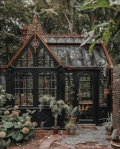 a black house with lots of windows and potted plants in the front garden area