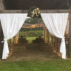 an outdoor barn with hay bales and lights on the ceiling, covered in white drapes