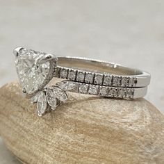 an engagement ring and wedding band are sitting on top of a piece of rock,