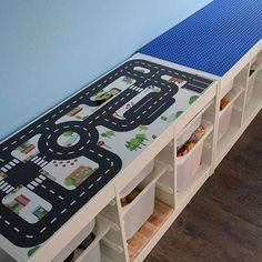 a child's play table with storage bins and toy cars on the top