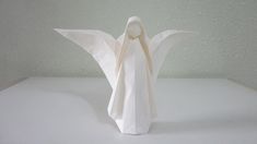 a white paper angel standing on top of a white surface with its wings spread out