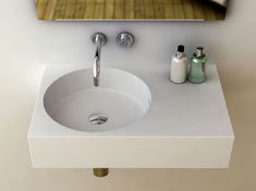 a white sink sitting under a mirror next to a faucet and soap dispenser