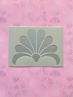 a close up of a flower on a pink and white wall with fan pattern behind it