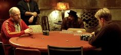 a group of men sitting around a red table playing cards in a pub or bar