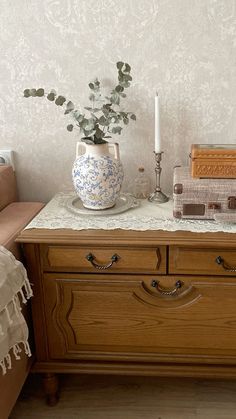 a wooden dresser with two vases on top of it next to a candle holder