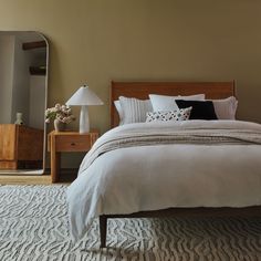 a bedroom with a bed, dresser and mirror in the corner that has been placed on top of a carpeted floor