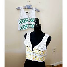 two crocheted vests sitting on top of a mannequin