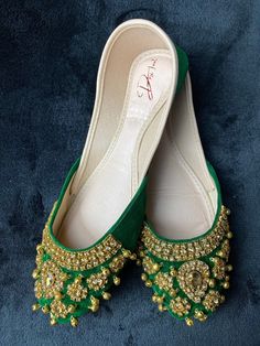 The Royal Green & Gold Jubilee Khussa is more than just a shoe, it's a statement offering a perfect blend of style and comfort, allowing you to dance the night away at weddings, festive celebrations, or cultural gatherings. The Royal Green and Gold Jubilee Khussa features a rich green velvet base, meticulously handcrafted using premium quality materials to ensure unmatched comfort and durability. The luxurious gold embellishments, adorned with shimmering diamonds, embellish every inch of this kh Festive Bridal Accessories With Stone Work, Bridal Accessories With Stone Work For Festive Occasions, Festive Bollywood Bridal Accessories For Wedding, Bollywood Style Bridal Accessories For Reception, Festive Bollywood Bridal Accessories With Tilla, Traditional Meenakari Bridal Accessories For Festive Season, Green Traditional Wear With Stone Work For Wedding, Bollywood Bridal Accessories With Pallu For Festivities, Bollywood Style Wedding Shoes For Festive Occasion