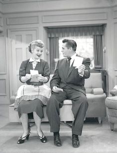 an old photo of two people sitting on a couch in a living room, one holding papers and the other reading