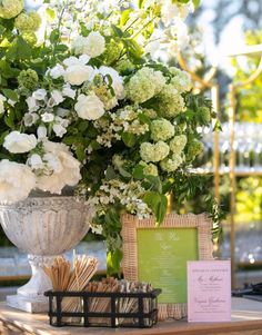 a table topped with a vase filled with white flowers next to a card and menu