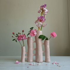 three vases with flowers in them sitting on a table next to each other,