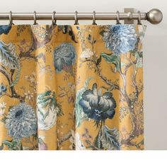 a yellow curtain with blue and green flowers on it, hanging from a metal rod