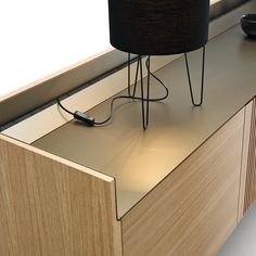 an electronic device is plugged in to the side of a wooden cabinet with a black lamp on top