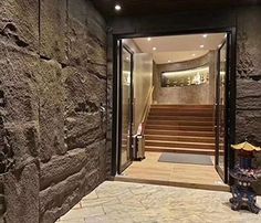 an entry way with stone walls and steps leading up to the second floor, which is lit by recessed lighting